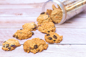 Butter cookies with black raisin were poured on the wood table from plastic bottle.