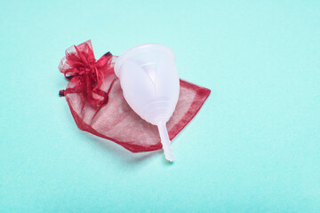 Eco-friendly siliconemenstrual cup with red package on green background.