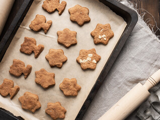 baked gingerbread cookies lie in a metal baking sheet on a brown table