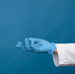 female hand in blue latex gloves on a blue background