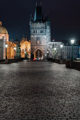 Naklejka premium paving and stone tower on Charles Bridge on Vltava river at night in the center of Prague