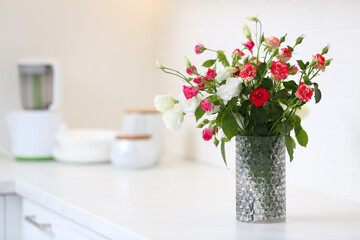 Obraz na płótnie Canvas Vase with beautiful flowers on white countertop in kitchen, space for text