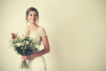 Young bride wearing wedding dress with beautiful bouquet on beige background. Space for text