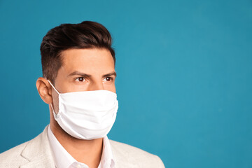 Man in protective face mask on blue background. Space for text