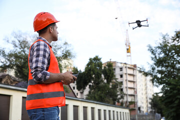 Builder operating drone with remote control at construction site. Aerial photography