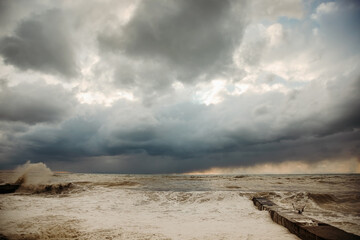 Storm waves near the shore on the beach. In the foreground, breakwaters.