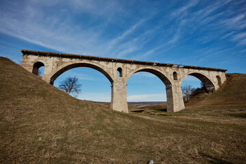 Fototapeta na wymiar Old destroyed narrow-gauge railway bridge of the arched type