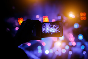 Man takes a picture of the show at the concert hall using a smartphone.