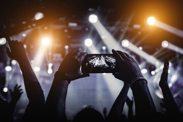 Man takes a picture of the show at the concert hall using a smartphone.