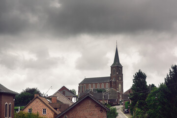Fototapeta na wymiar Church in rural village under clouded sky.