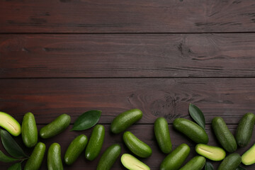 Fresh seedless avocados with green leaves on wooden table, flat lay. Space for text