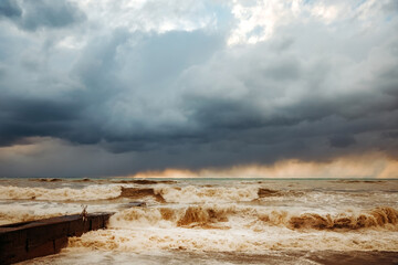 Storm waves near the shore on the beach. In the foreground, breakwaters.