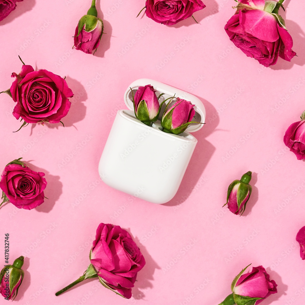 Wall mural surprise for her for womens day. two little pink roses in charging case for earphones over pink back