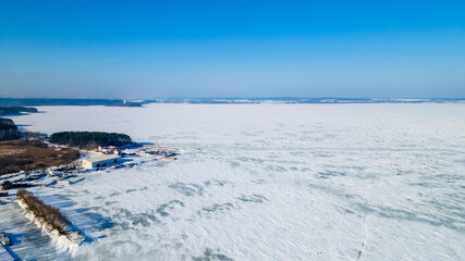 Aerial drone image of frozen lake and dam with snow. Ice from the drone view in winter. Beauty in nature concept.