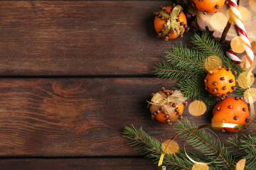 Flat lay composition with pomander balls made of fresh tangerines and cloves on wooden table, space for text