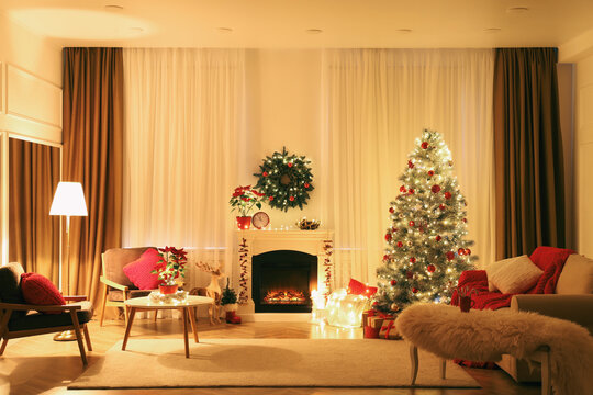 Beautiful living room interior with burning fireplace and Christmas tree in evening