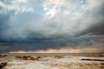 Storm waves near the shore on the beach. In the foreground, breakwaters.