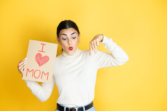 Beautiful Woman Celebrating Mothers Day Holding Poster Love Mom Message Surprised, Looking Down And Pointing Down With Fingers And Raised Arms