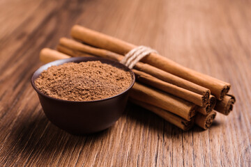 Cinnamon powder and sticks on wooden table
