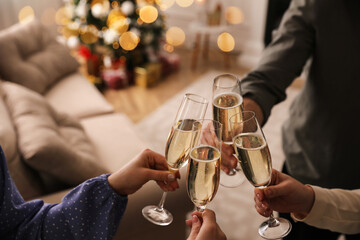 People clinking glasses with champagne at home, closeup