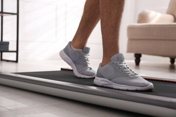 Man training on walking treadmill at home, closeup © New Africa
