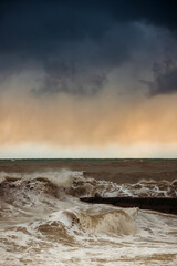 Storm waves near the shore on the beach. In the foreground, breakwaters.