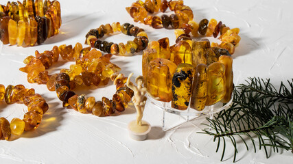 Variety of beautiful orange and yellow amber bracelets on a white plastered background. 