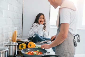 Single father with his daughter is at home together at daytime. Preparing food