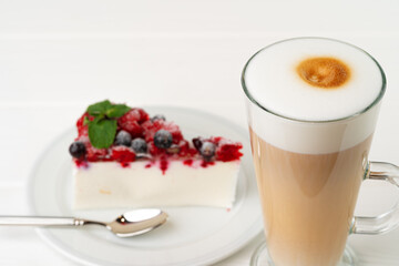 Cup of latte coffee with piece of berry cheesecake