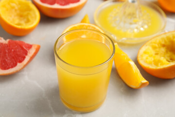 Freshly made orange juice, fruits and squeezer on table, closeup