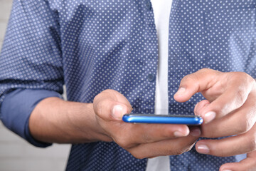 Close up of young man hand using smart phone.