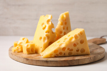Pieces of delicious cheese on white wooden table