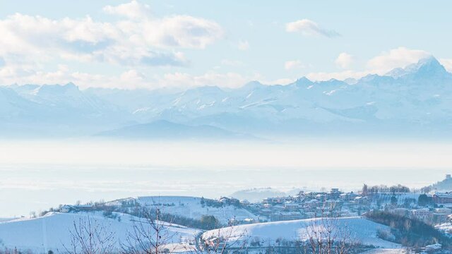 Pan: Italy Piedmont row of wine yards, unique landscape in winter with snow, rural village on hill top, italian historical heritage nebbiolo grape agriculture panoramic view