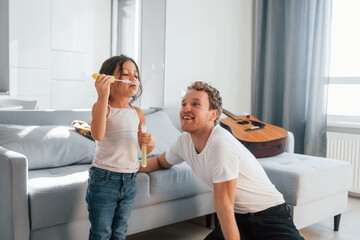 Single father with his daughter is at home together at daytime. Playing with bubbles