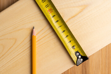 Yellow ruler on the wooden plank in carpenter's workshop. Selective focus.