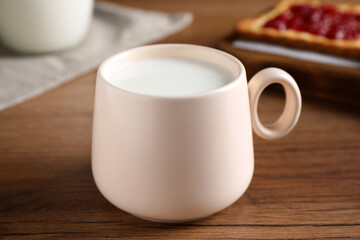 Fototapeta na wymiar Cup of fresh milk on wooden table, closeup