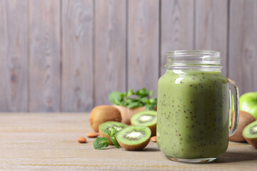 Delicious kiwi smoothie and fresh fruits on wooden table. Space for text