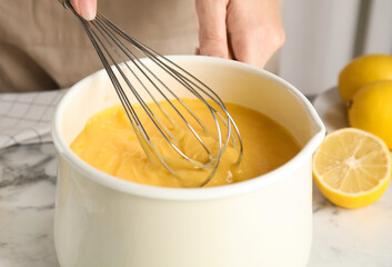 Woman cooking delicious lemon curd at white marble table, closeup