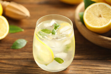 Cool freshly made lemonade in glass on wooden table, closeup