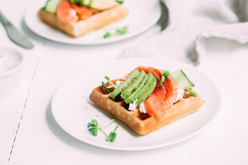 Belgian waffles with salmon, avocado and cream cheese on a white plate. Healthy breakfast