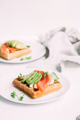 Belgian waffles with salmon, avocado and cream cheese on a white plate. Healthy breakfast