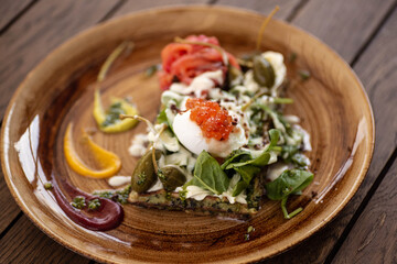 Hearty breakfast of eggs benedict with salmon. Viennese spinach waffles with poached egg, salmon, red caviar, capers and herbs. Hearty and healthy breakfast. Beautiful and colorful food..