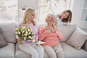 Photo portrait of granddaughter shut eyes of granny making surprise with postcard tulips flowers...