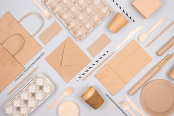 Flat lay composition with eco-friendly tableware and kraft paper food packaging on gray background....