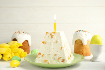 Traditional cottage cheese Easter paskha with dried apricot and burning candle on white wooden table