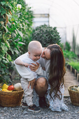 Woman playing with her child in a greenhouse with flowers