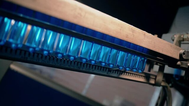 Inserting empty plastic bottle preforms into a conveyor belt