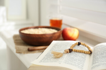 Fototapeta na wymiar Holy Bible with prayer beads on window sill indoors, closeup. Great Lent season