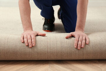 Worker rolling out new carpet flooring indoors, closeup