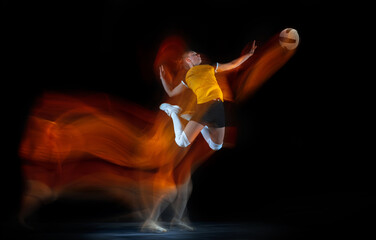 Young female volleyball player isolated on black studio background in mixed light. Woman in...